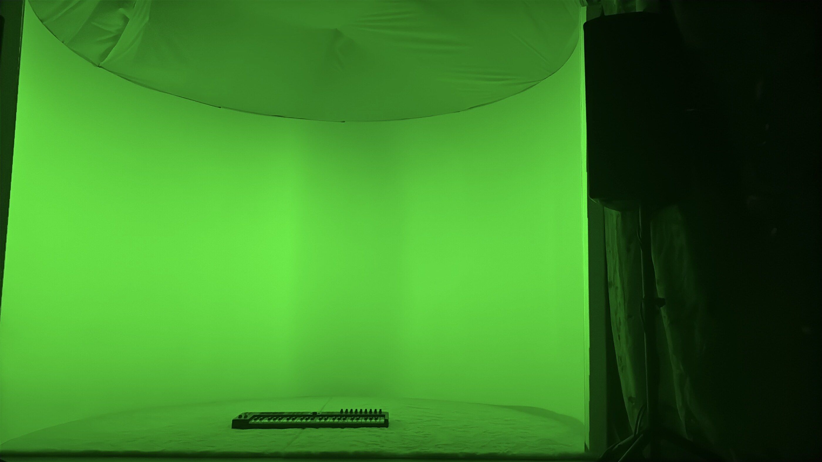 The empty installation, the whole curved wall flooded green, the keyboard alone on the floor.